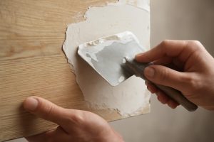mains-appliquer-platre-surface-bois